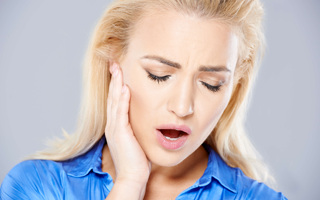Woman holding her jaw in pain from a TMJ disorder