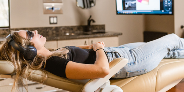 Patient relaxing in the dental chair with headphones and sunglasses