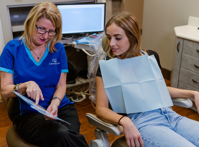 Dental team member explaining a treatment plan to a patient in the dental chair